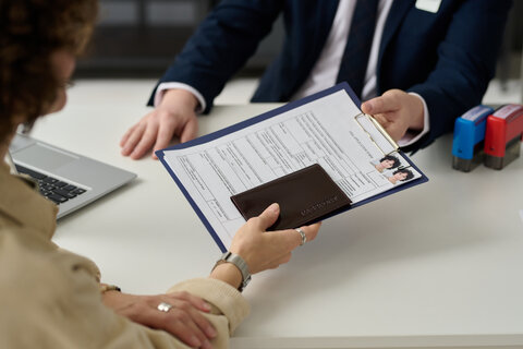 Image of a lady handing over an application to a man in an office set up